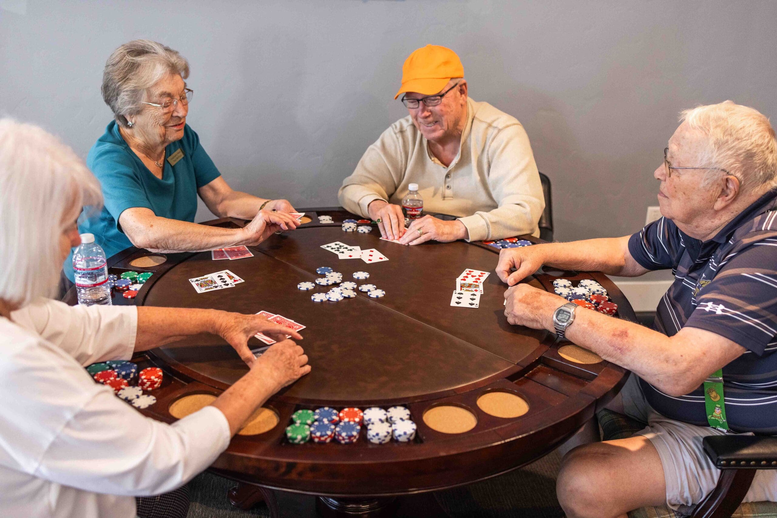 A group of seniors sit at a poker table engaged in a game at The Summit of Coralville.