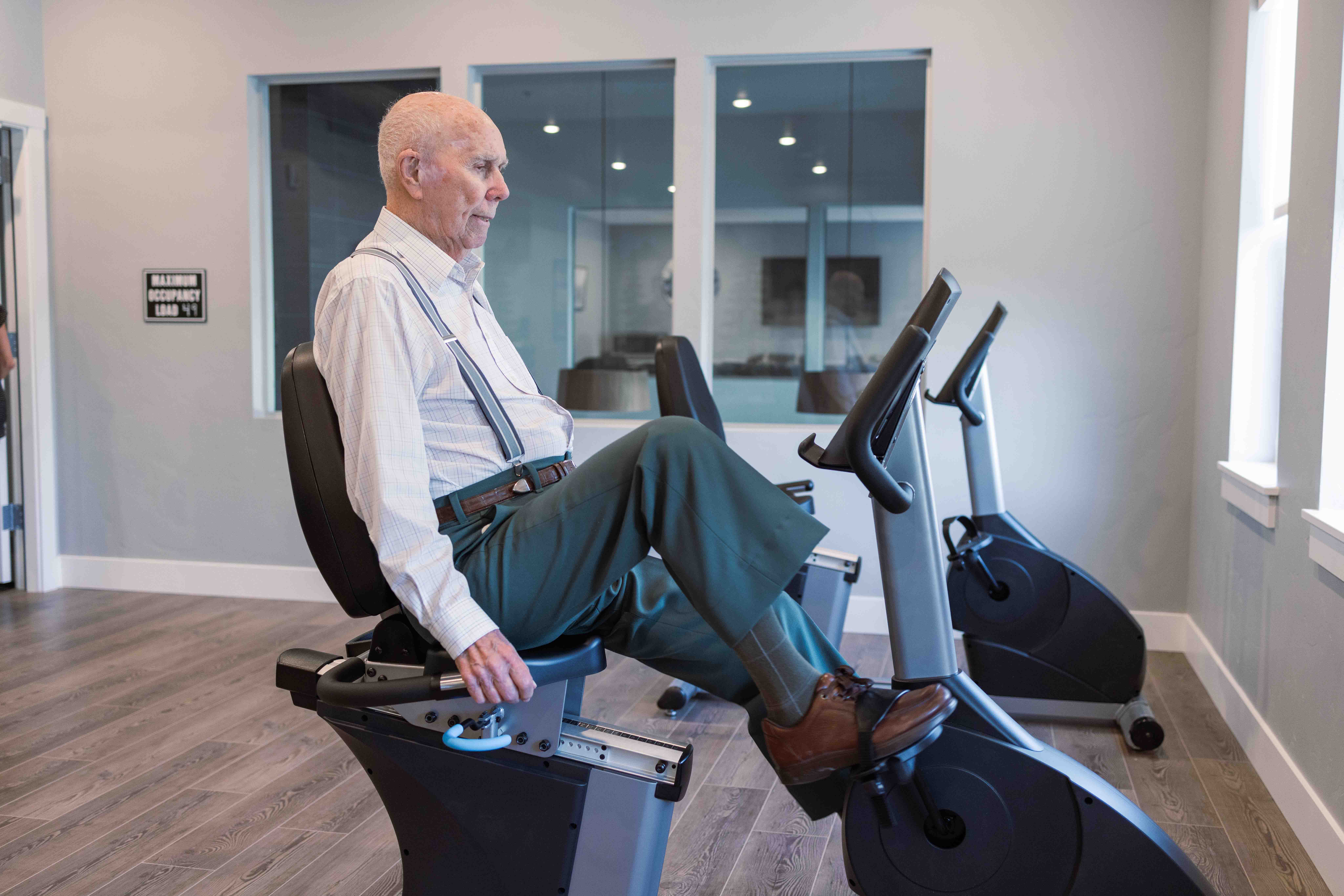 A senior man uses a bike machine in the gym at The Summit of Coralville.