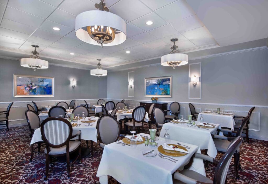 Interior image of The Summit of Coralville's dining room with white linen tables and flatware.