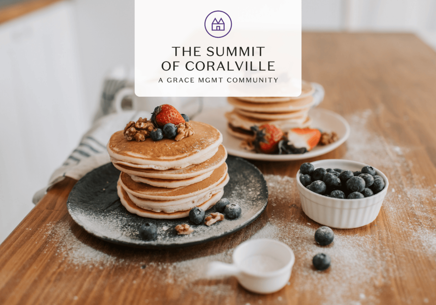 Stack of fluffy pancakes topped with strawberries, blueberries, and walnuts on a dark plate